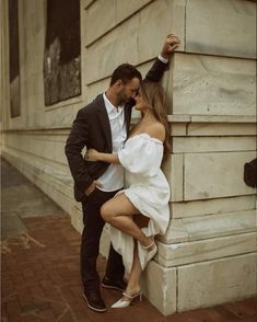 a man and woman leaning against a wall