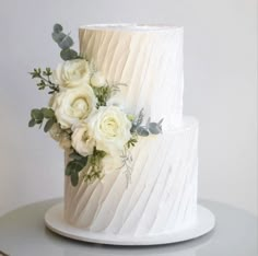 a wedding cake with white flowers and greenery