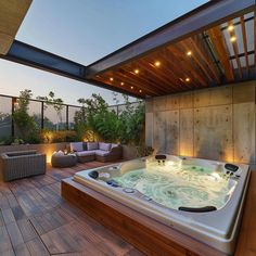 a large hot tub sitting on top of a wooden floor next to a patio area