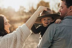 a man and woman holding a small child in their arms while they are smiling at each other