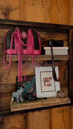 a wooden shelf with purses and other items on it's sides, including a pink handbag