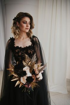 a woman in a black dress with flowers and feathers on her head is posing for the camera