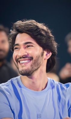 a man with long hair smiling at the camera