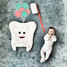 a baby is laying on the floor next to a toothbrush and balloon shaped object