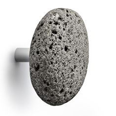 three gray rocks sitting next to each other on a white surface with two hooks in front of them