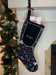 a christmas stocking hanging from a fireplace next to a tree with presents on it