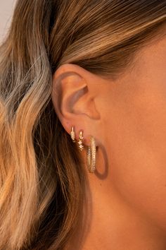 a close up of a person wearing gold earring designs on their left ear and right ear