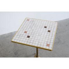 a white and gold tiled table on a metal stand