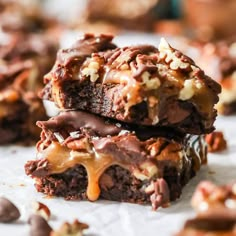 two chocolate brownies with nuts and caramel drizzled on top are stacked up