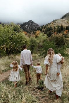 a man and two children are walking in the grass with their parents on a cloudy day