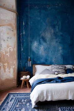 a bedroom with blue walls and rugs on the floor, along with a bed