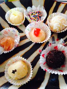 there are many different desserts on the black and white plate with red, yellow, and blue sprinkles