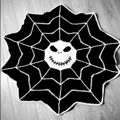 a crocheted halloween rug with a smiling face on the center and spider web in the middle