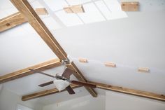 a ceiling fan is hanging from the ceiling in a room with white walls and wood beams