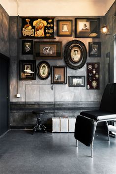 a black chair sitting in front of a wall with pictures on it