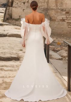 a woman in a white wedding dress is standing on the stairs looking over her shoulder