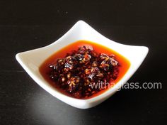 a small white bowl filled with food on top of a black table next to a glass bottle