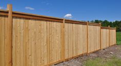 a wooden fence in the middle of a field with grass and blue sky behind it