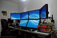 four computer monitors sitting on top of a desk