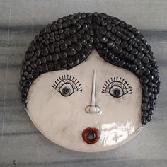 a ceramic face with black hair and eyes