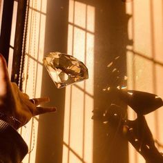 a person reaching for a diamond in front of a window with sunlight streaming through it