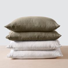 three pillows stacked on top of each other, one in white and the other in khaki