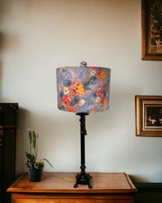 a lamp that is sitting on top of a table next to a potted plant