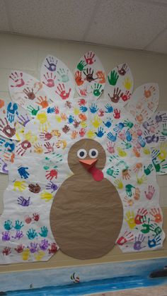 a turkey made out of handprints on a bulletin board in a school hallway