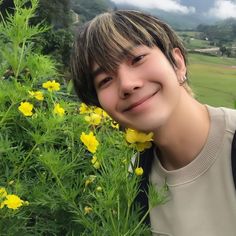 a young man standing next to yellow flowers