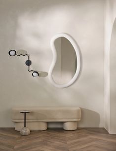 a white bench sitting next to a wall mounted mirror on the side of a wall