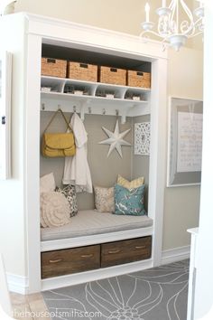 a white coat rack filled with lots of pillows and other items next to a chandelier