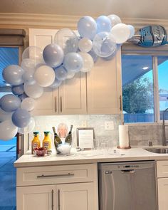 the balloons are hanging from the ceiling above the kitchen sink and dishwasher,