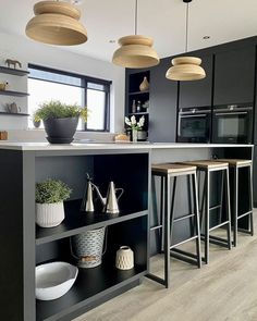 an image of a modern kitchen setting with bar stools and potted plants on the island