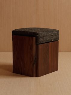 a wooden box with a black seat cover on it's sides and a wood floor in the background