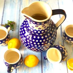 a blue and white pitcher filled with tea next to lemons