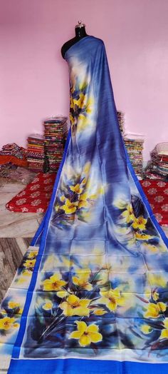 a blue and yellow flowered scarf on display in front of a pink wall with other items