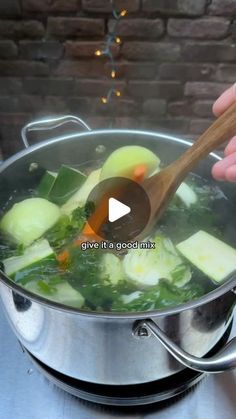 someone is stirring vegetables in a pot with a wooden spoon