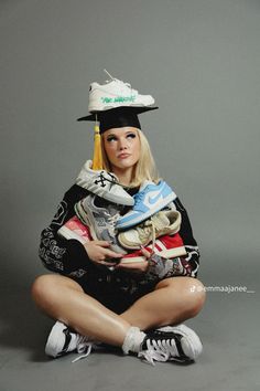 a woman sitting on the ground with shoes in her hand and wearing a graduation hat