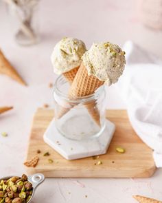 two scoops of ice cream sitting in a glass jar on top of a cutting board