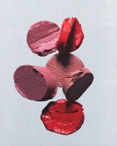 four lipsticks are stacked on top of each other in the air, with one being painted red