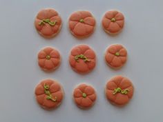 small orange decorated cookies with green bows on them sitting on a white table top next to each other