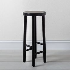 a black stool in front of a white wall