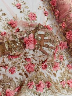 pink and gold floral embroidered fabric with sequins on white background, closeup