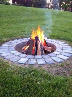 a fire pit in the middle of some grass