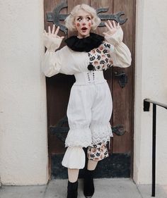 a woman in white dress standing next to a door with wrenches on her head