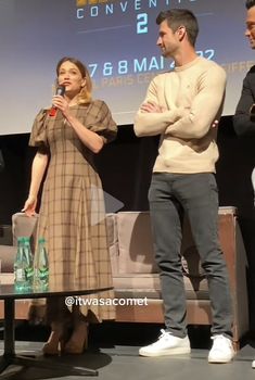 three people standing in front of a screen talking