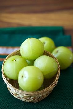 a basket filled with green apples sitting on top of a table