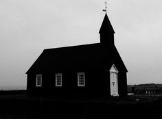 an old black church with a steeple and cross on top