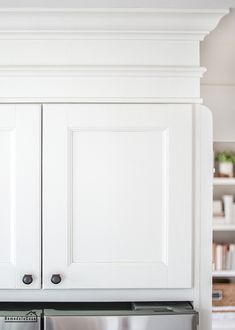 a kitchen with white cupboards and stainless steel dishwasher in the center area