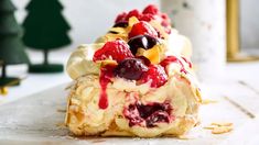 a pastry with fruit and cream on it is sitting on a table next to a christmas tree